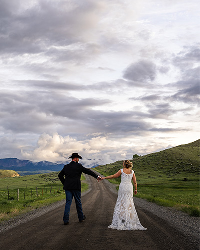 Photo of wedding couple holding hands on a road by Hannah Lee Films